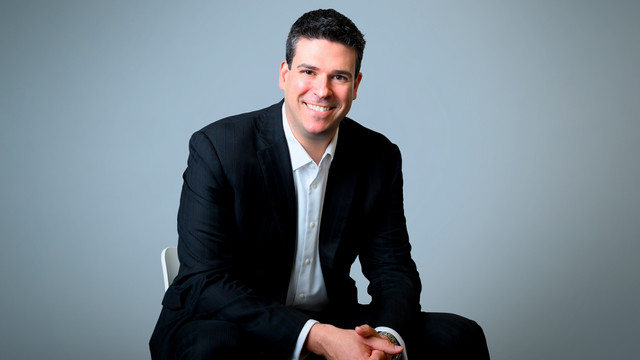 Headshot of 1998 alumnus Gregory Hayken in a black suit jacket and white-collared shirt