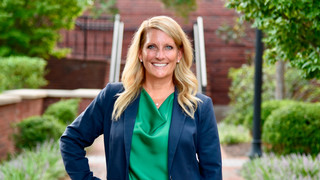 Headshot of Amy Amick, '94, wearing a navy blazer and green blouse