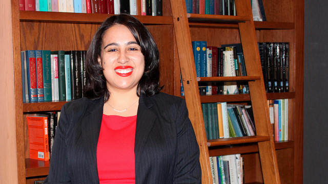 Isabella Sabogal standing by a bookshelf in the Jepson Faculty Lounge