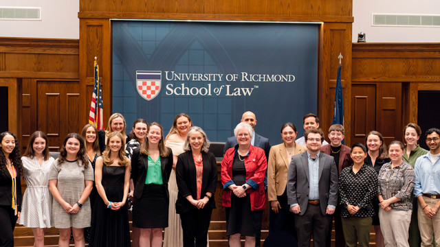  A group of people stand in front of the Richmond Law school logo.