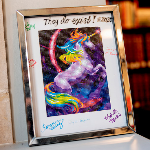 A photo of a framed piece of art depicting a rearing unicorn with the words 