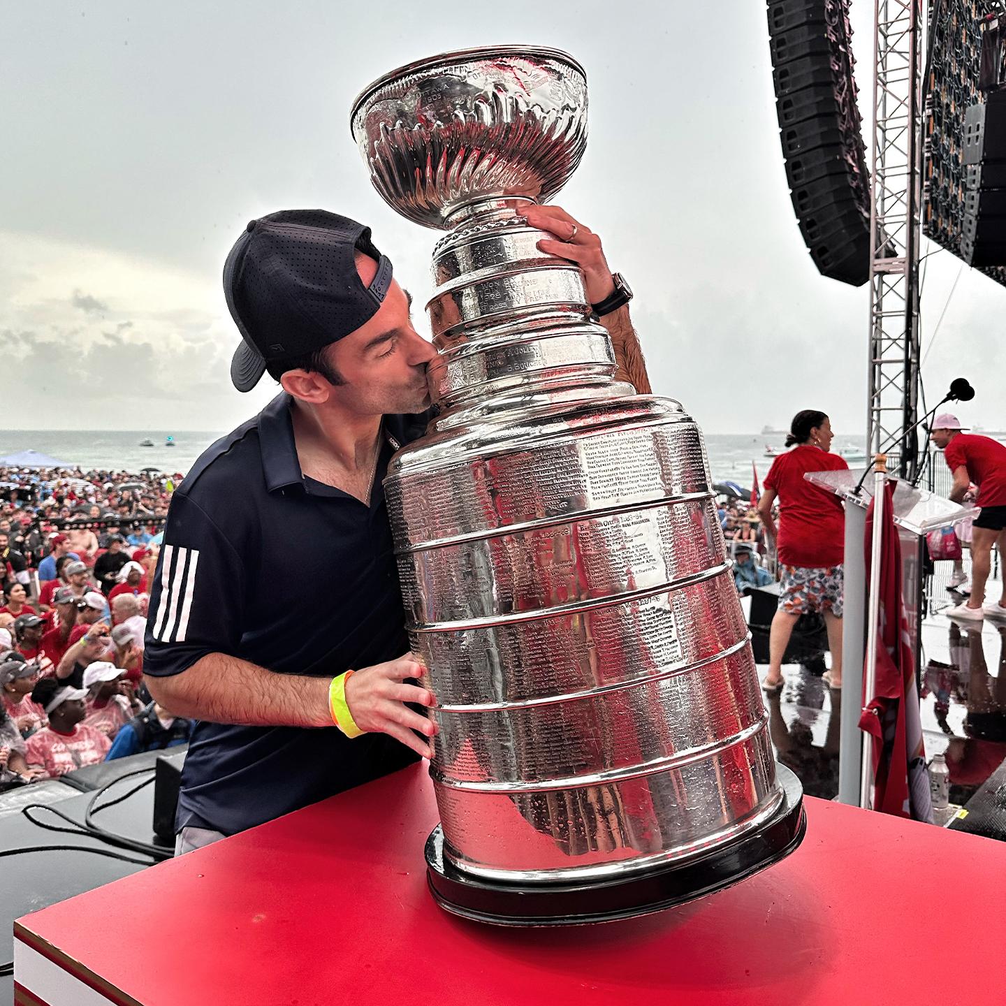 A man wearing a hat kisses the Stanley Cup