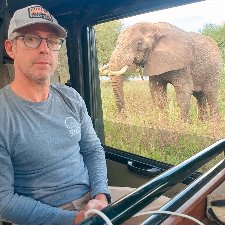Dave Salley sits in a jeep with an elephant behind him.