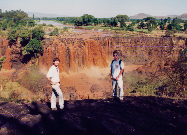 An old photo of Mark and Dave in front of a waterfall.