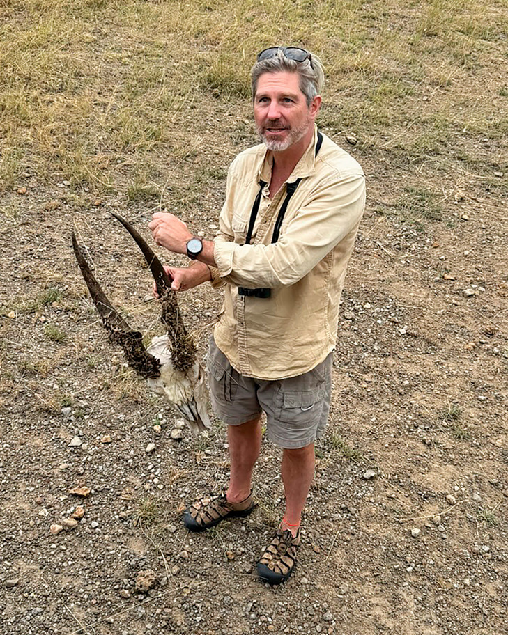 Mark holding a skull of an animal while out on safari.