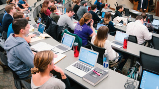Classroom of students listening to lecture with laptops open