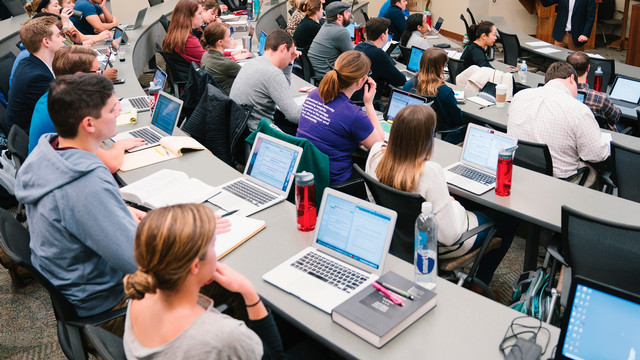 Classroom of students listening to lecture with laptops open
