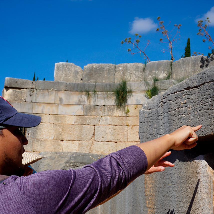 Students view stone inscriptions at a historic site at Delphi