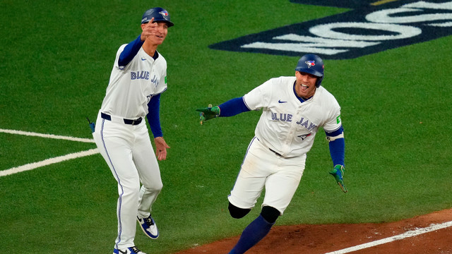 Toronto Blue Jays first base coach Mark Budzinski, left, cheers on George Springer, right, who rounds the bases after hitting a three-run home run against the Seattle Mariners during the seventh inning in Game 7 of baseball's American League Championship Series in Toronto, Monday, Oct. 20, 2025.
