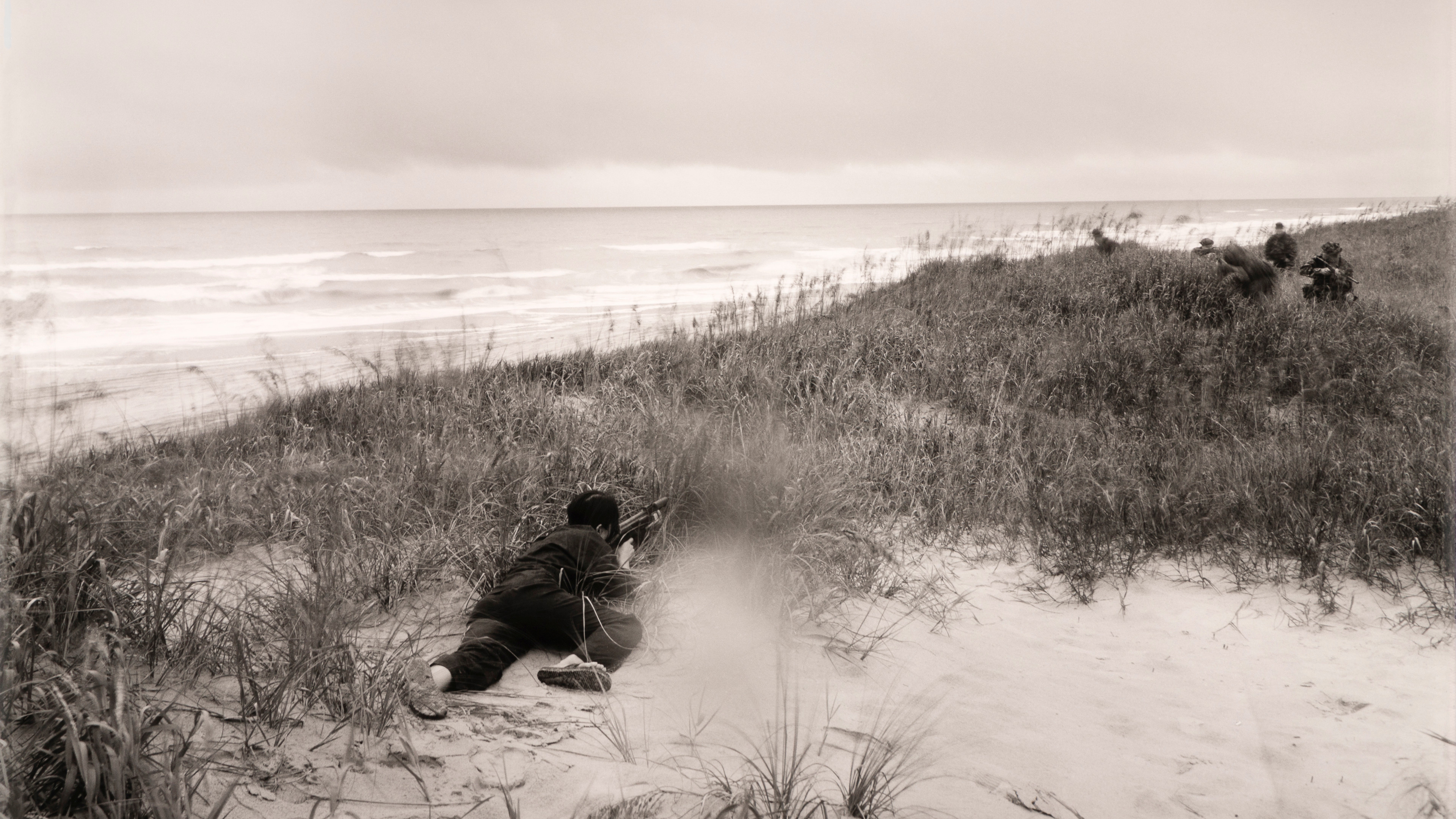 A photograph of a person in a sand dune during a reenactment of the Vietnam War.