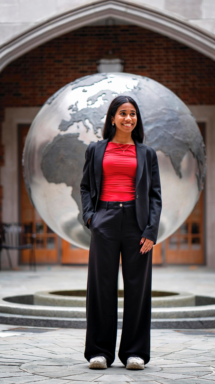 A photo of Neha Kalwala in front of a large globe statue.