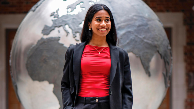 A photo of Neha Kalwala in front of a large globe statue.