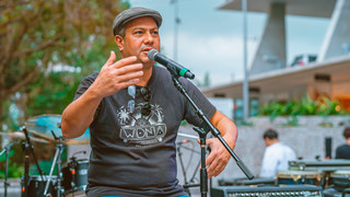 A photo of Gene de Souza with a microphone.