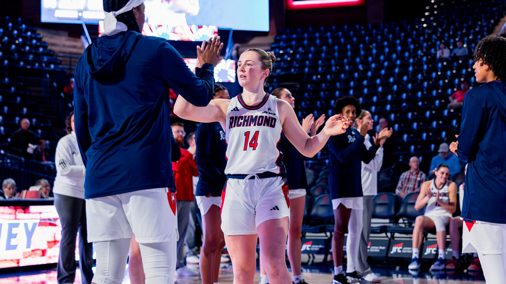 A photo of Ally Sweeney high-fiving a member of the women's basketball staff.