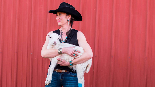 A photo of Katherine Harrison holding a baby lamb.