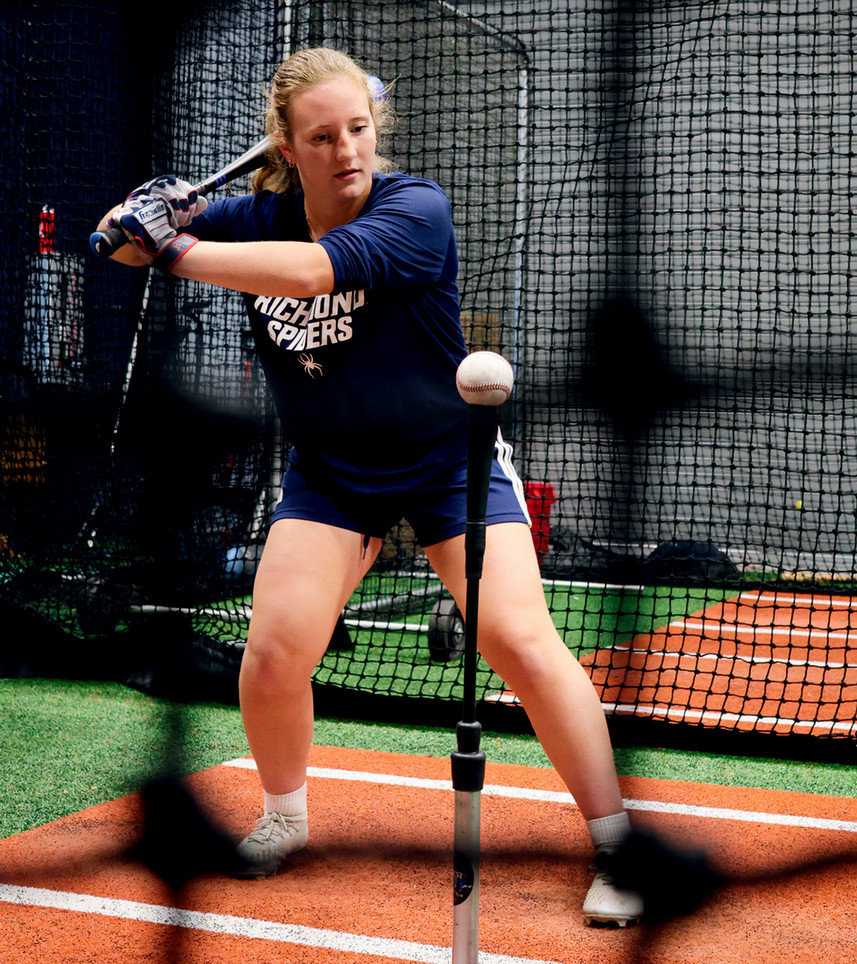 Marisa Snee practices batting from a tee in the batting cages. 