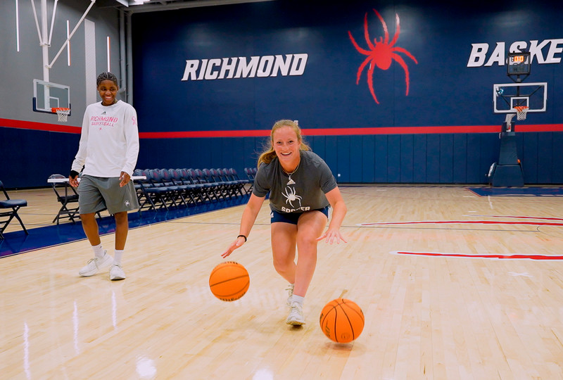 Marisa Snee practices a two-handed dribbling drill with two basketballs, while guard Alicia Newel looks on.