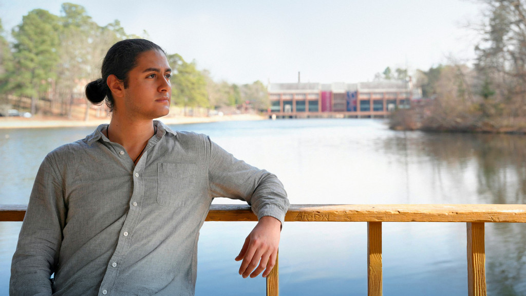 A photo of Ibrahim Alkaseer on campus at the gazebo with Westhampton Lake, and the commons in the background.