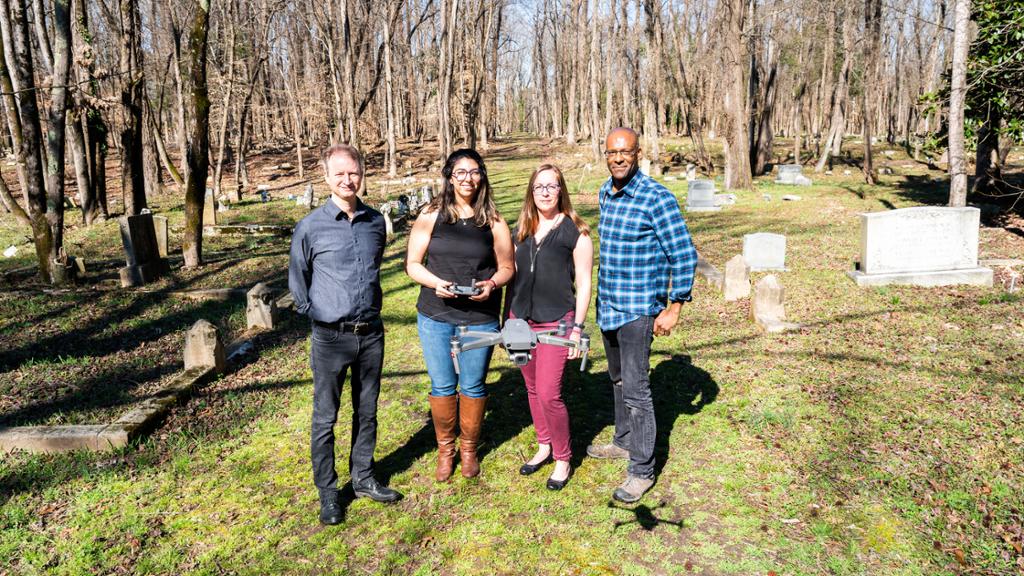 four people in a cemetery with a flying drone