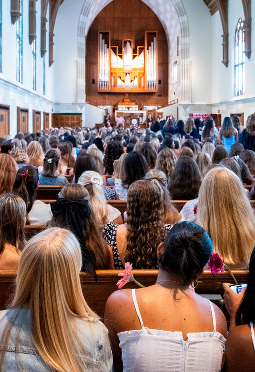 Looking from the back of Cannon Memorial Chapel toward the front during Proclamation 2026, with the backs of students wearing dresses in the foreground 