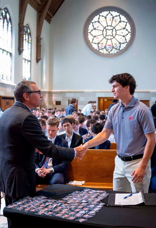 Richmond College student shaking administrator's hand at front of Cannon Memorial Chapel