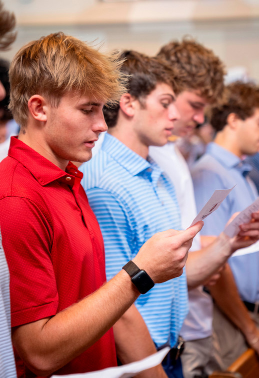 Row of Richmond College students in red and blue polo shirts reciting honor pledge