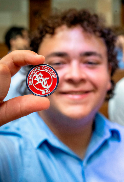 Richmond College student holds college coin up to the camera