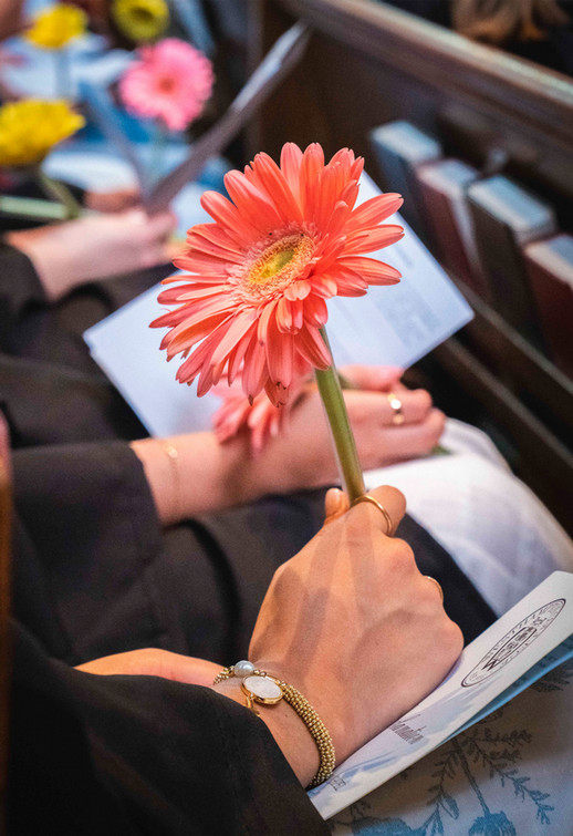 A Westhampton College student holding a pen with a salmon-colored daisy-like flower attached to the top