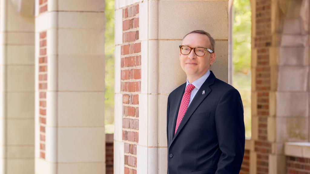 Incoming University of Richmond president Kevin Hallock, standing in front of a building on campus.