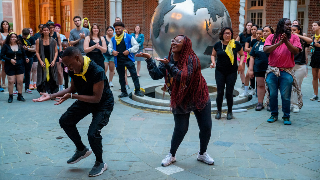 Students dancing in front of a globe and crowd at UR