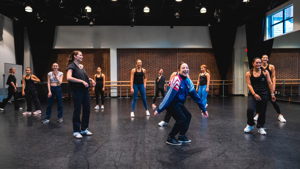 dance students with choreographer in rehearsal hall