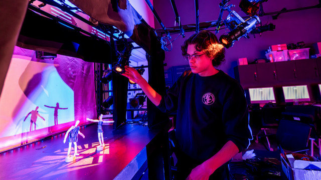 student focuses miniature theatrical lights on a model stage
