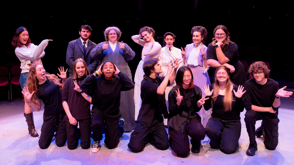 theater cast and crew pose together on stage following a performance