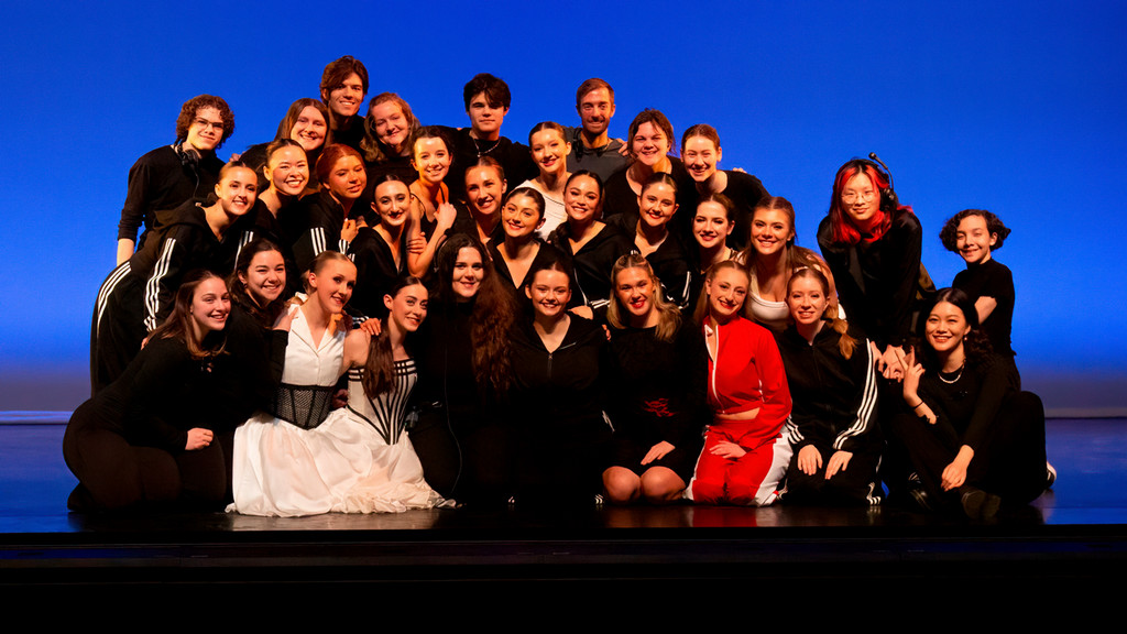 dance cast and crew pose together on stage following a performance