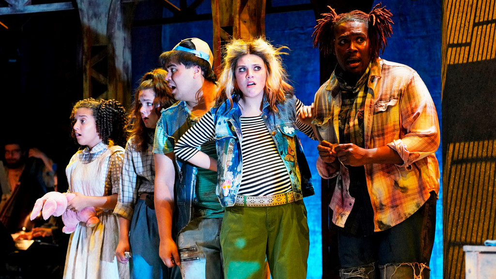 cast of college student actors on stage during a performance looking surprised