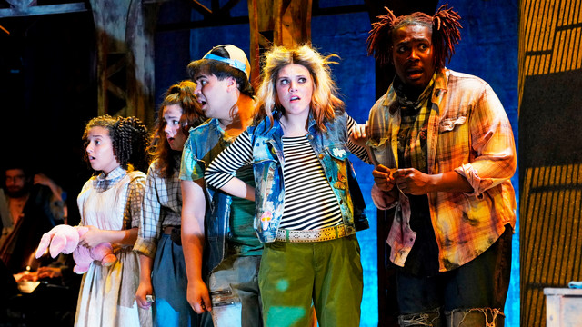 cast of college student actors on stage during a performance looking surprised