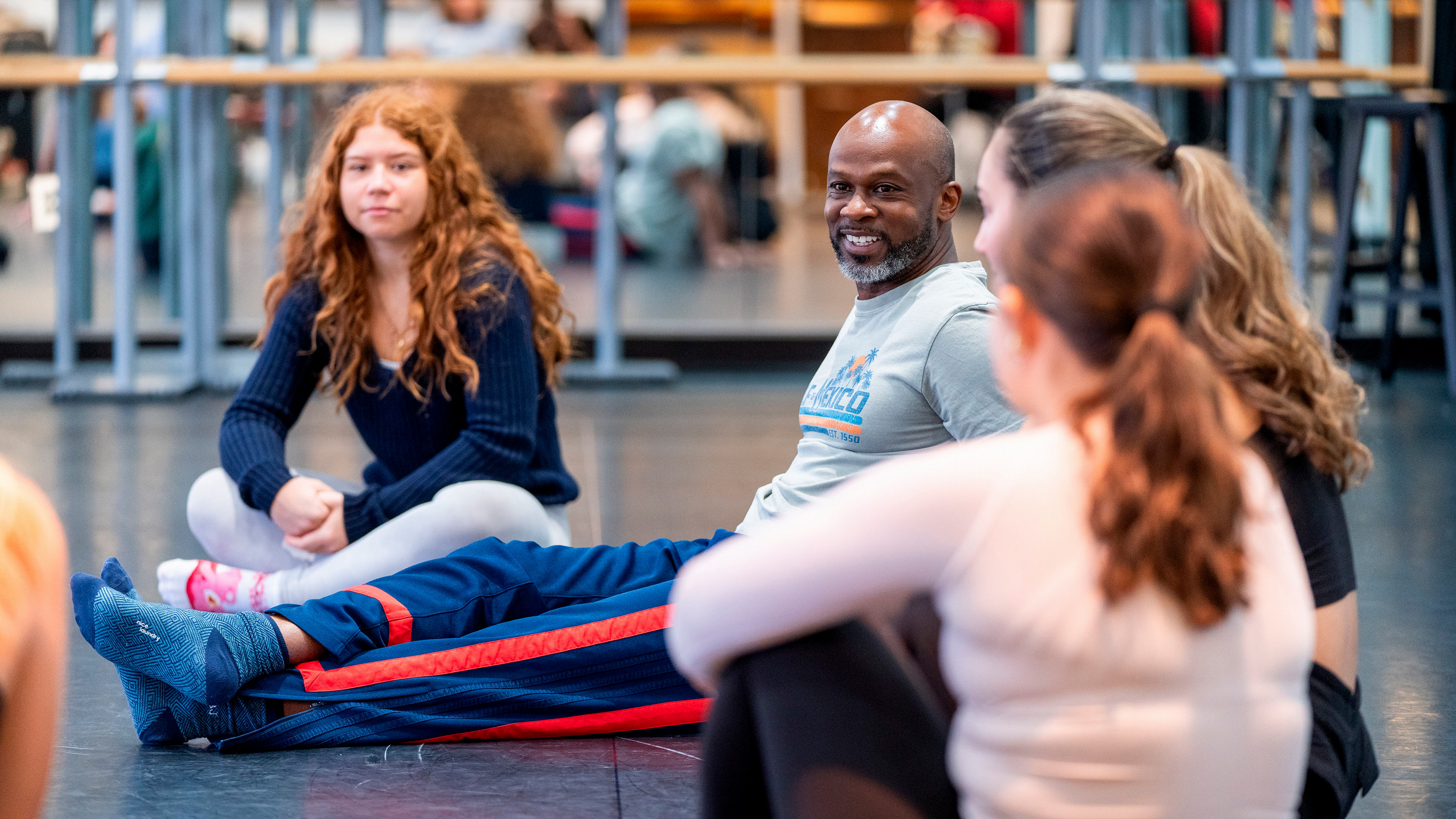 Artist in residence Mark Bamuthi Joseph sitting and talking with students in a dance studio at the University of Richmond