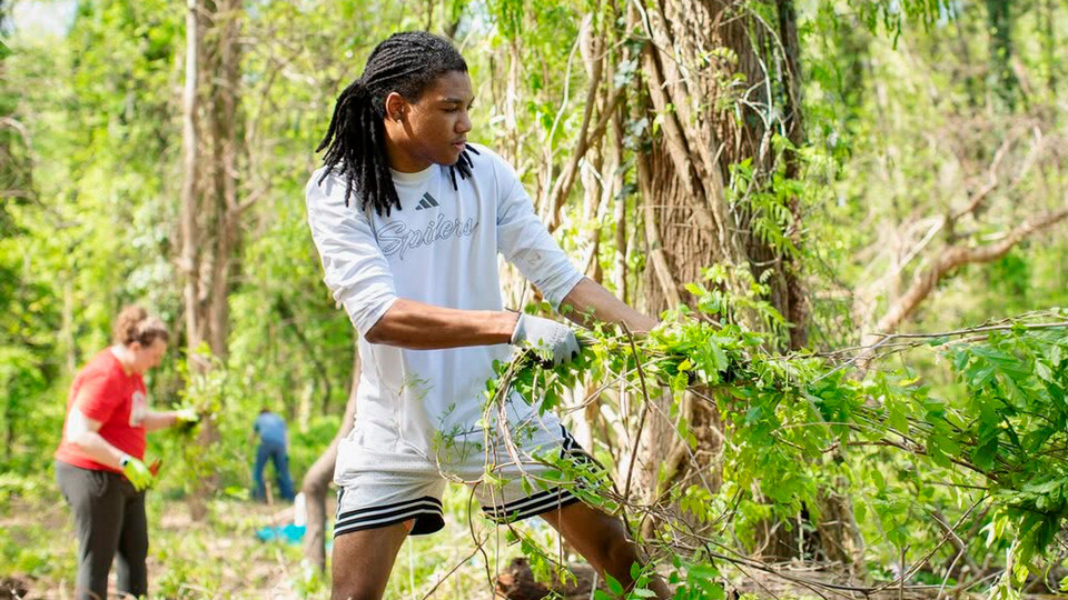 A University of Richmond student working to clear weeds at East End Cemetery in Richmond Virginia.