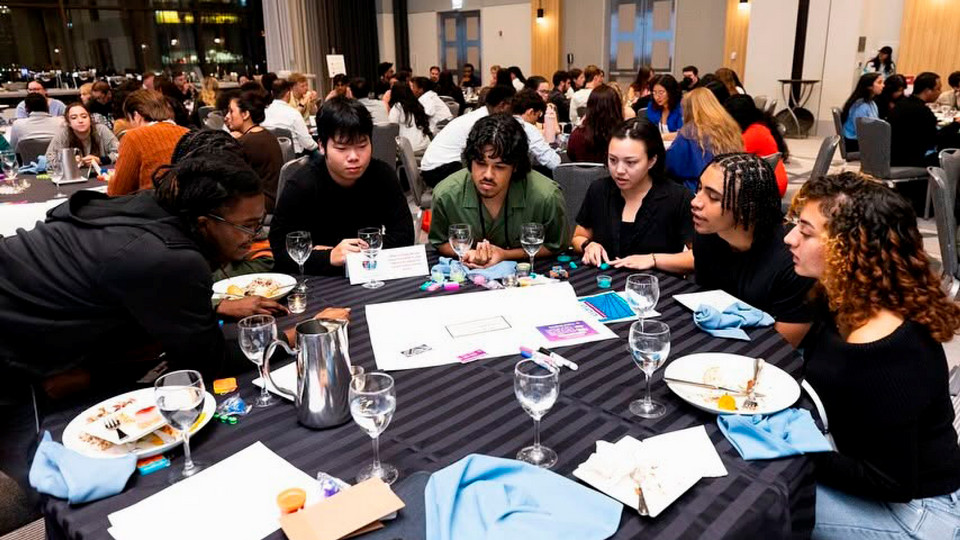 A photo of  group of Newman fellows, including Devin Morgan, working together at a conference
