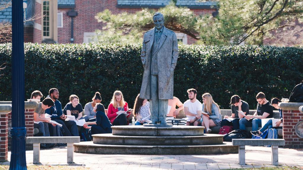 Students participating in a class outdoors around the Robins statue.