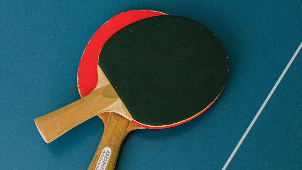 two ping pong paddles resting on a blue table