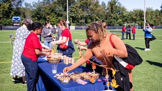 A group of employees gathers around a table to create a fall craft