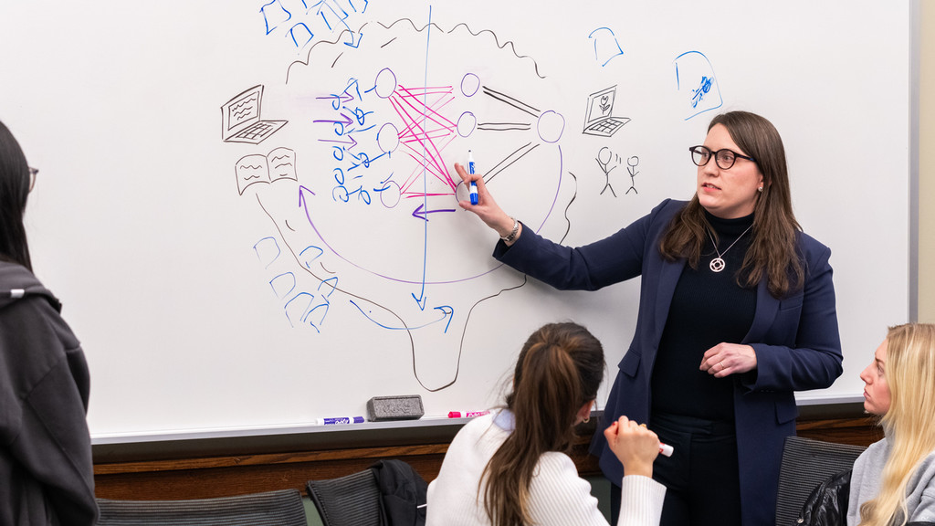 Professor Lauren Tilton standing at a whiteboard in front of three students 