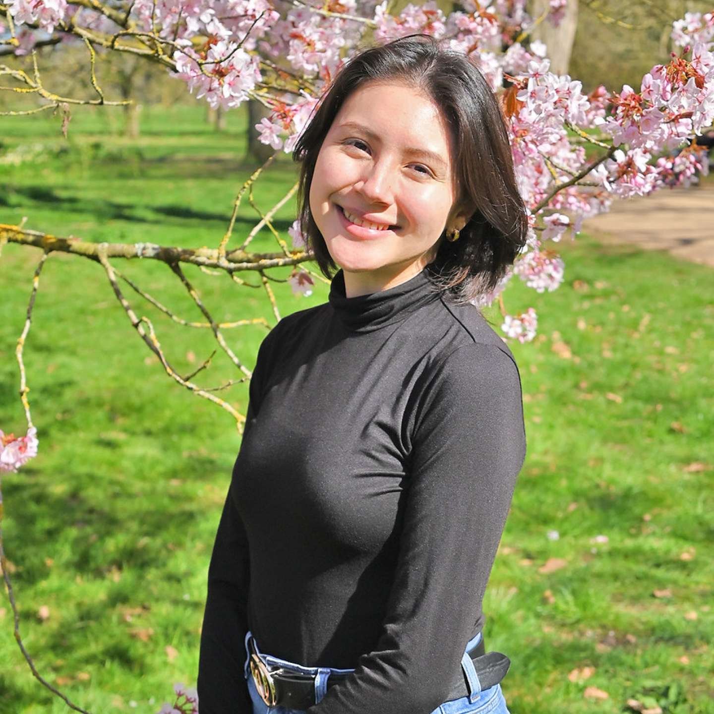 An environmental portrait of Sarah Schalkoff standing on front of a cherry blossom tree.
