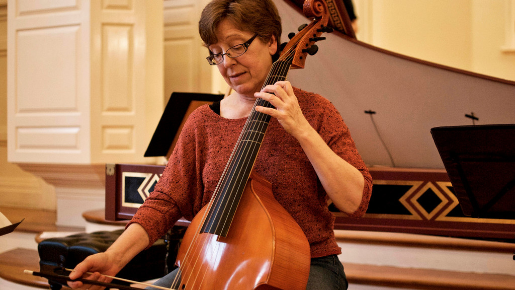 Lisa Terry sits and bows the viola da gamba