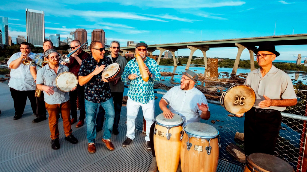 Latin jazz group Kadencia stands on a bridge with the Richmond skyline in the background