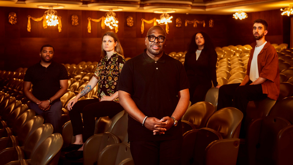 Christian McBride and band Ursa Major posing together in an ornate empty auditorium