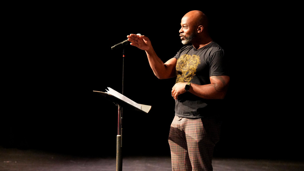 poet and performer Marc Bamuthi Joseph recites a poem in a theater