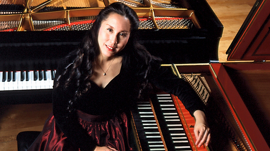 keyboardist Joanna Kong sits in front of a piano and harpsichord