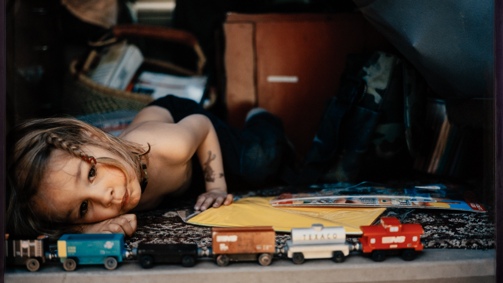 Little boy laying on his side playing with trains